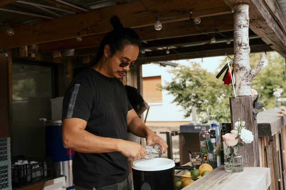Barkeeper an der überdachten Holzbar im Garten