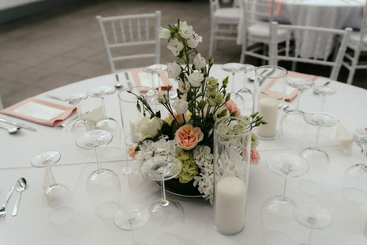 Runder Tisch im Gewächshaus mit Blumen, Kerzen in Glas und umgedrehten Weingläsern